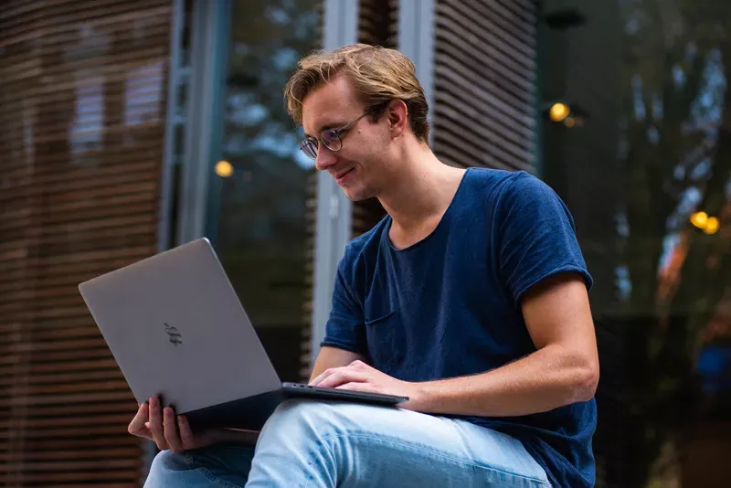 young man using a laptop while sitting outside